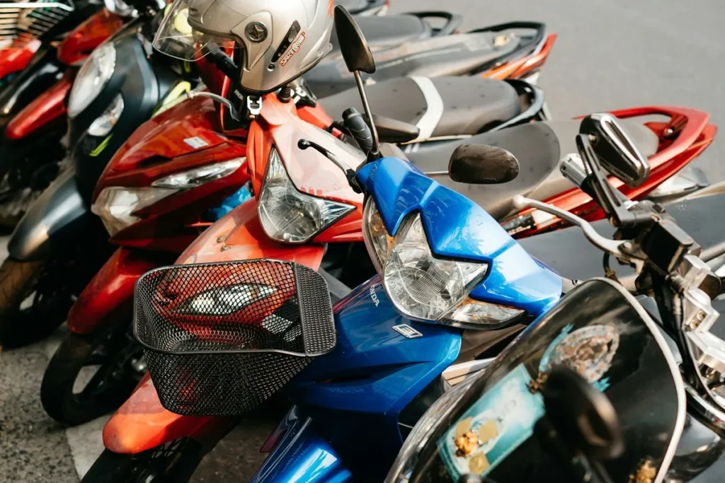 Várias motos estacionadas em rua urbana, incluindo uma moto azul em destaque.