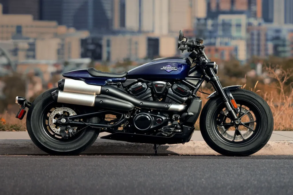 Moto Harley-Davidson azul estacionada em área urbana, destacando design moderno, escape duplo e estilo esportivo.