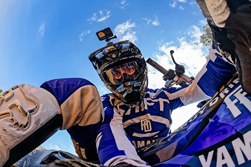 Piloto de motocross usando câmera acoplada ao capacete para capturar imagens em primeira pessoa durante a pilotagem.