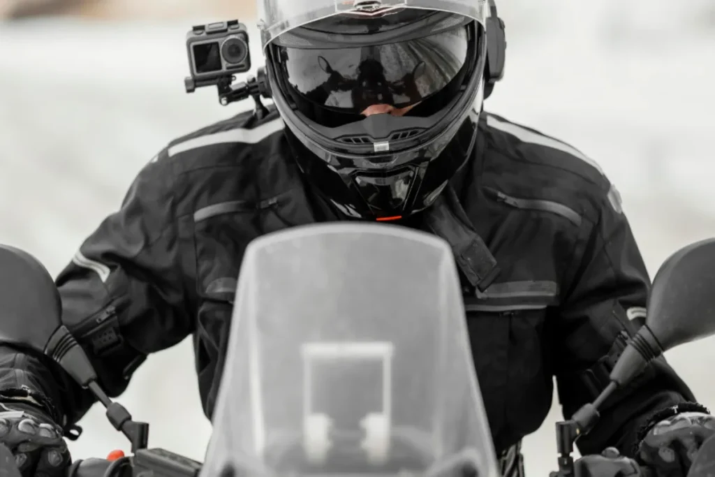 Motociclista com capacete preto equipado com câmera de ação lateral, ideal para registrar viagens e aventuras em duas rodas.