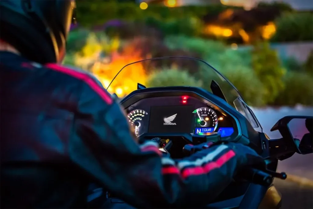 Motociclista observando painel digital iluminado de uma moto Honda em funcionamento à noite