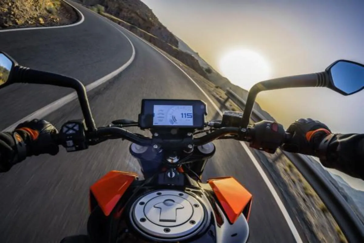 Motociclista pilotando em estrada curva ao pôr do sol com painel digital moderno em destaque